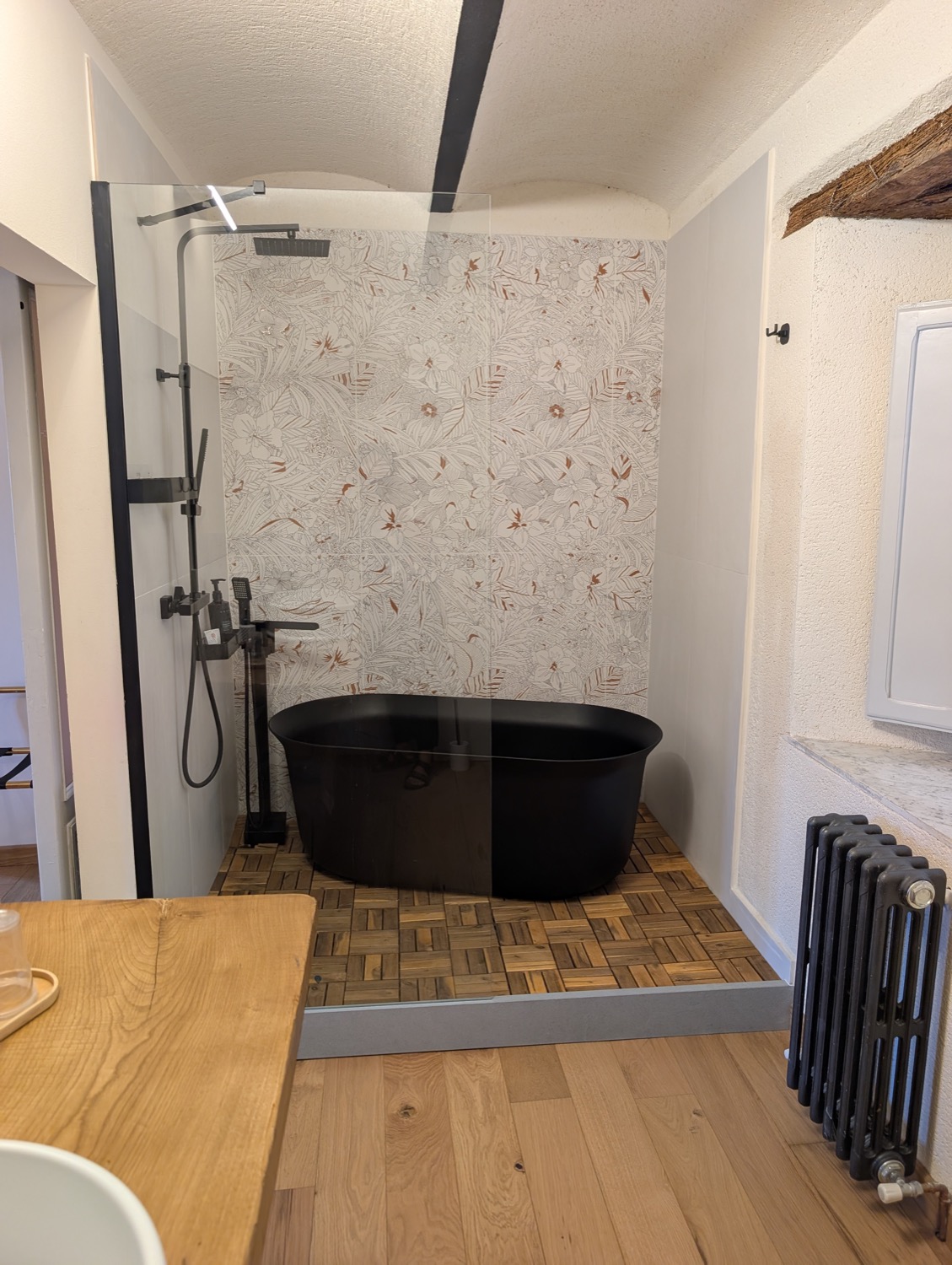 Bagno della camera Lilium — vasca freestanding nera e carta da parati floreale