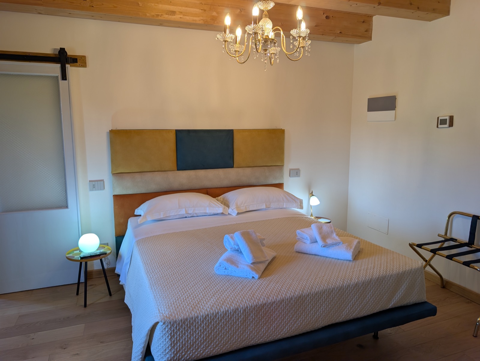 Camera Magnolia — letto matrimoniale con testiera patchwork e lampadario di cristallo